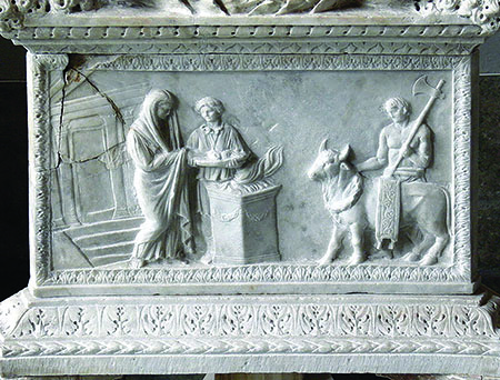 Ejemplo de un relevo romano que representa una escena de sacrificio, con libaciones sobre una ara en la que arde un lÃquido inflamable. A la derecha, el victimarius con una machada apoyada en el hombro.